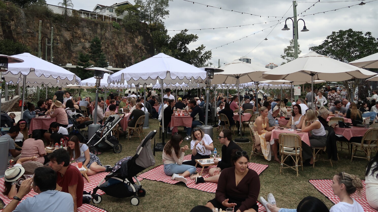 A crowd of people seated on picnic tables and mats